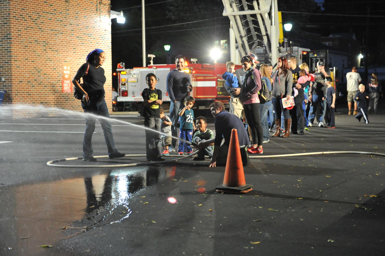 Kid spraying fire hose at fire station open house