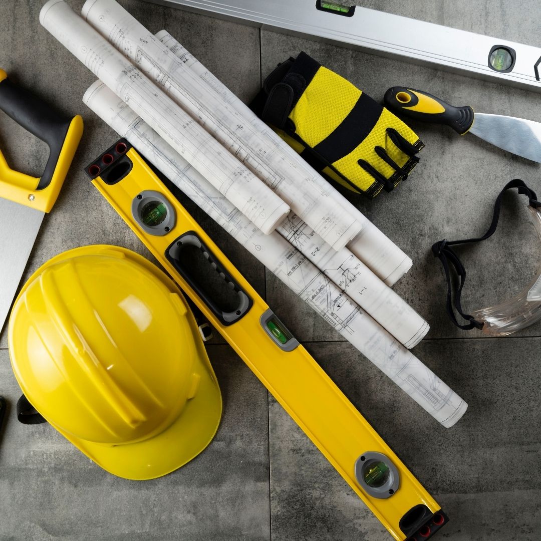 Image of yellow construction hat, site plans, and other construction tools.